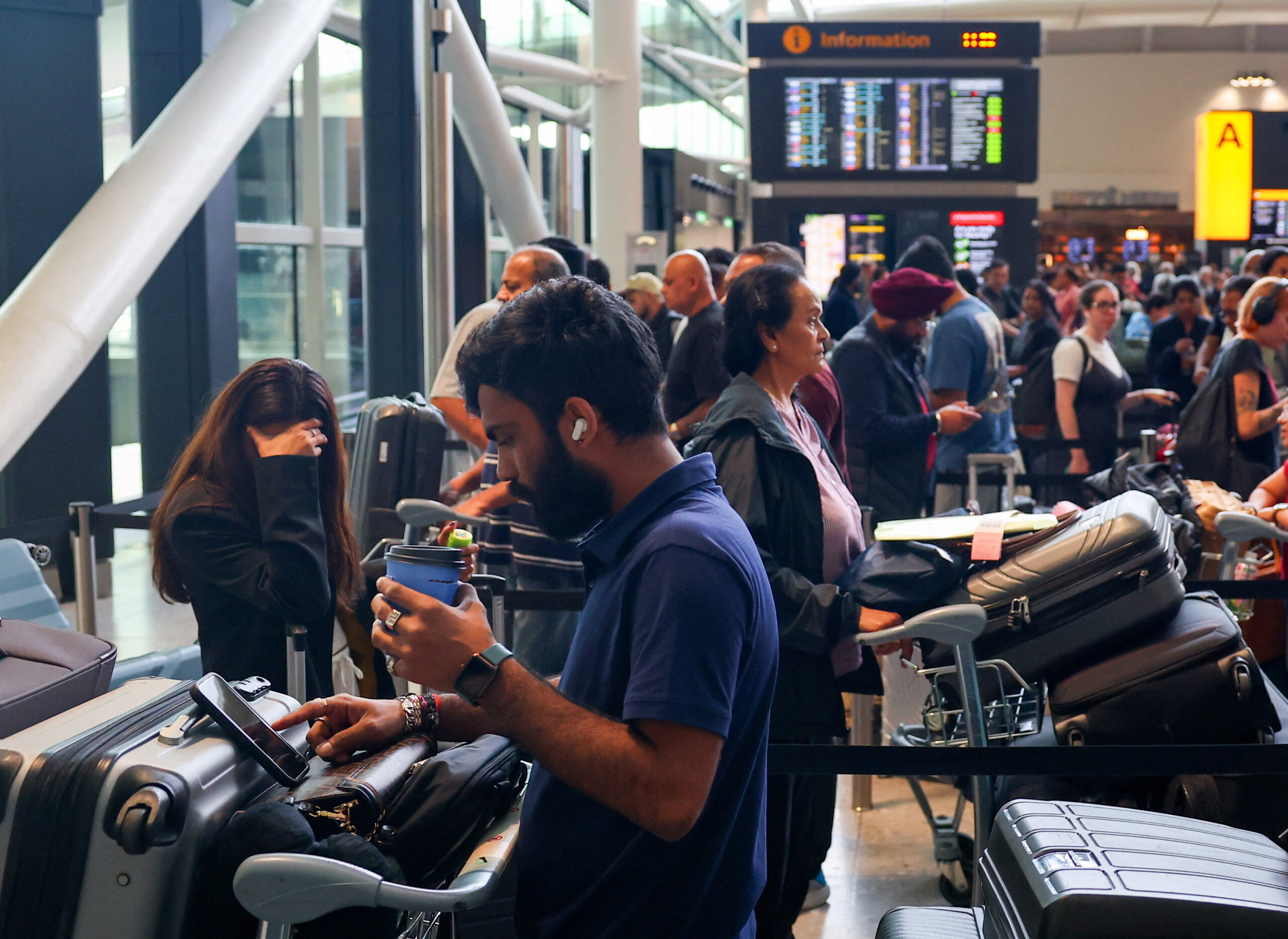 Οι ταξιδιώτες περιμένουν κοντά στα γκισέ check-in στο Τερματικό 2 του αεροδρομίου Heathrow, εν μέσω καθυστερήσεων και ακυρώσεων πτήσεων, που οφείλονται σε διακοπή των συστημάτων check-in και επιβίβασης λόγω κυβερνοεπίθεσης