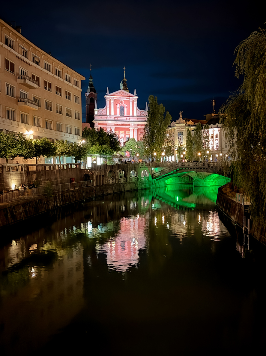 Ljubljana, Slovenia – July 14, 2025: Nightime view of the Ljubljanica River as it winds through the historic center of Ljubljana. Lined with trees, cafés, and charming riverside architecture